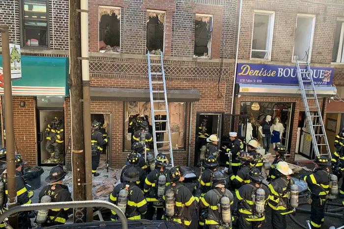 Firefighters stand outside a three story building with shattered windows from a fire in a suspected marijuana grow house in Brooklyn.